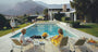 Two women sitting by a pool with mountains in the background
