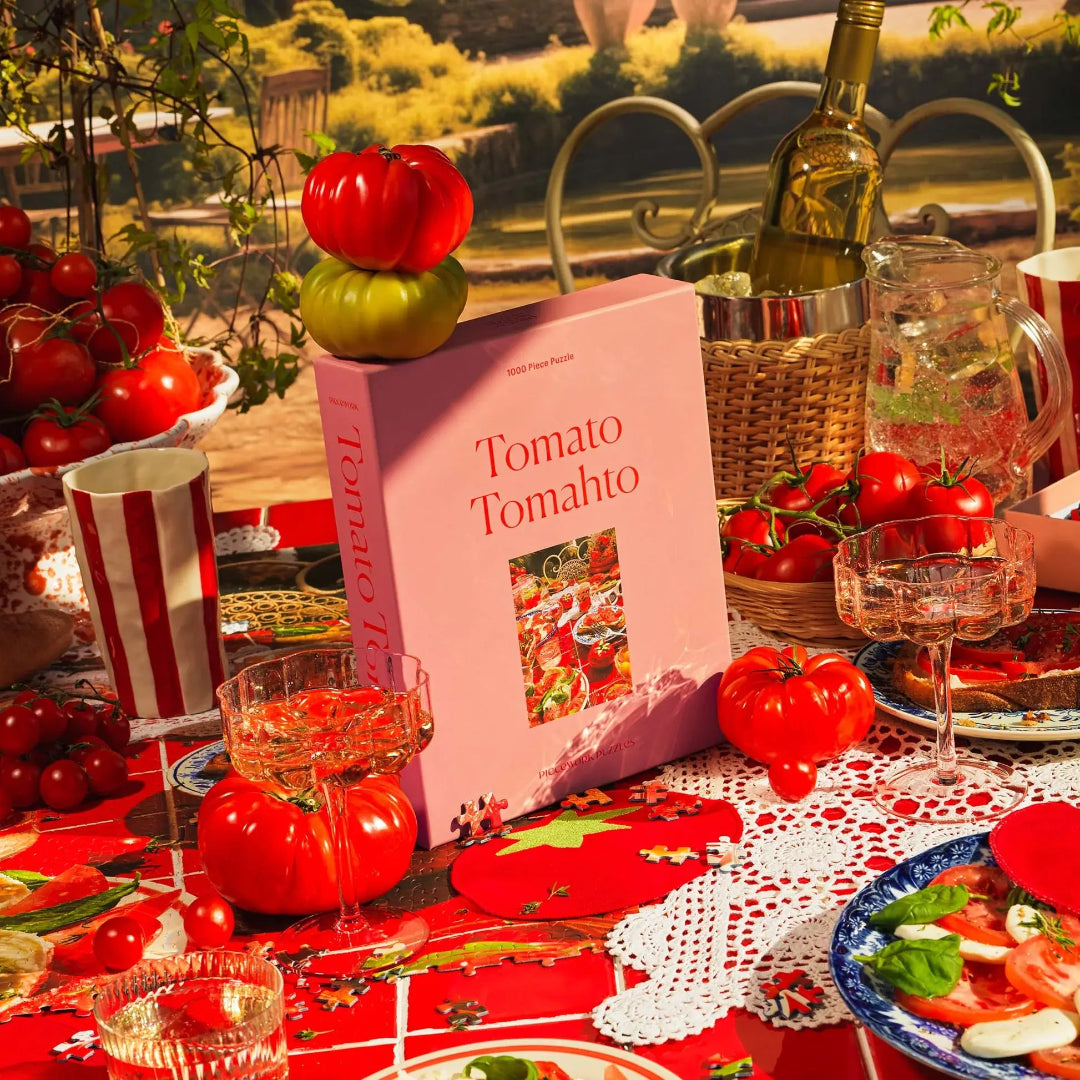 Table setting with tomatoes, the 'Tomato Tomahto' puzzle box, and wine glasses.