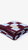 Folded checkered blanket with a brand label on a white background