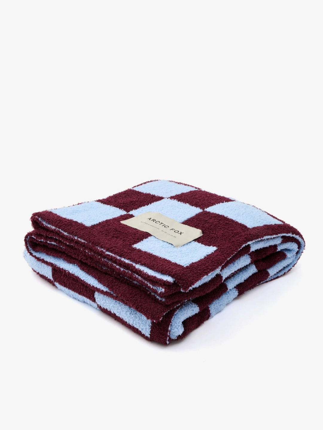 Folded checkered blanket with a brand label on a white background