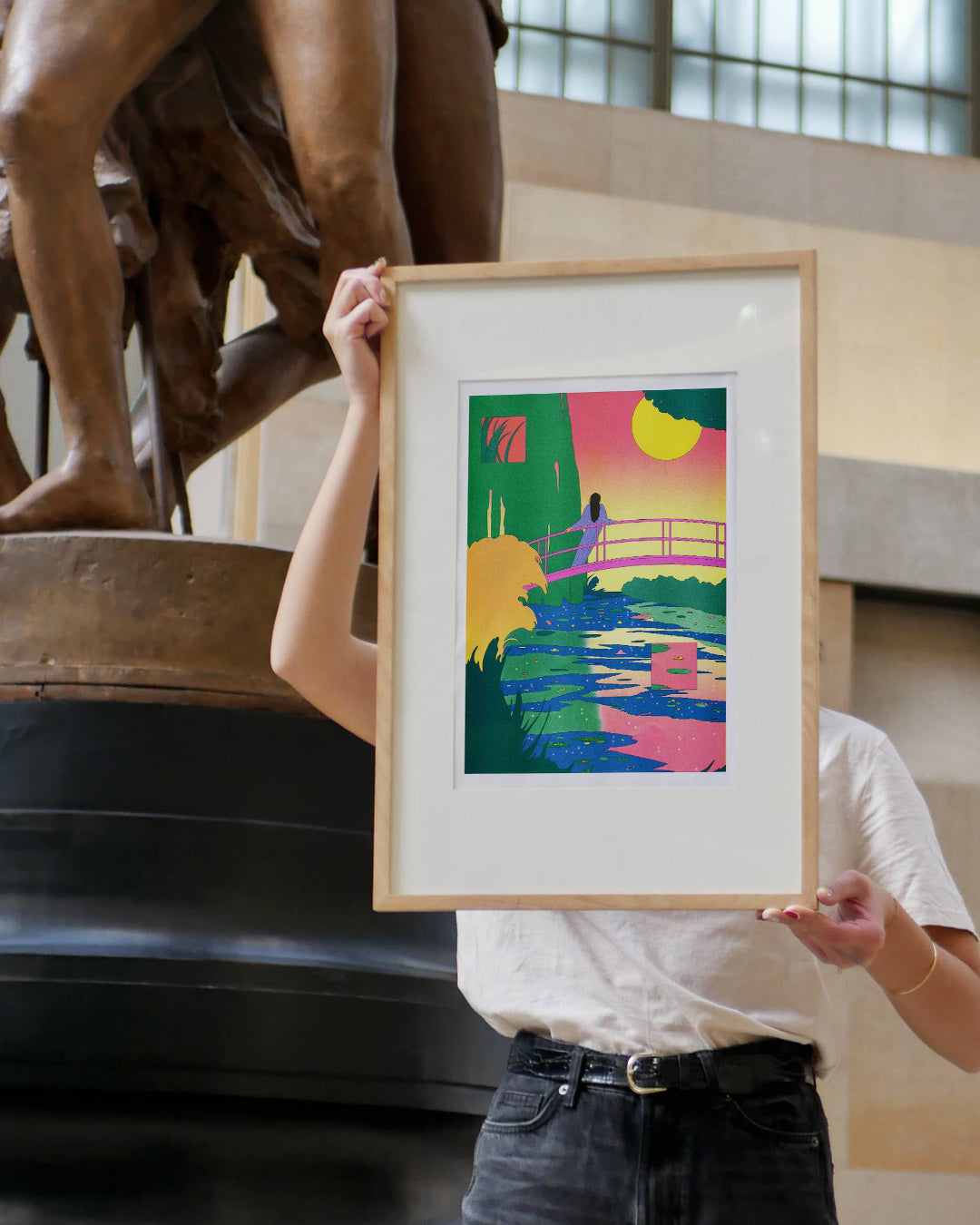 Person holding a framed colorful artwork in front of a statue
