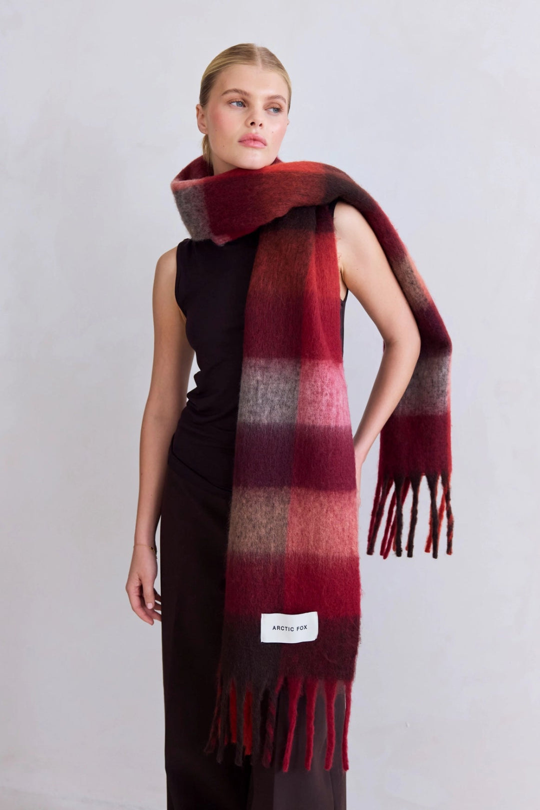 Model wearing a red and brown checkered scarf with a visible brand label on a light gray background