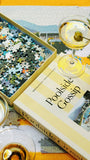 'Poolside Gossip' puzzle box with a martini on a yellow surface