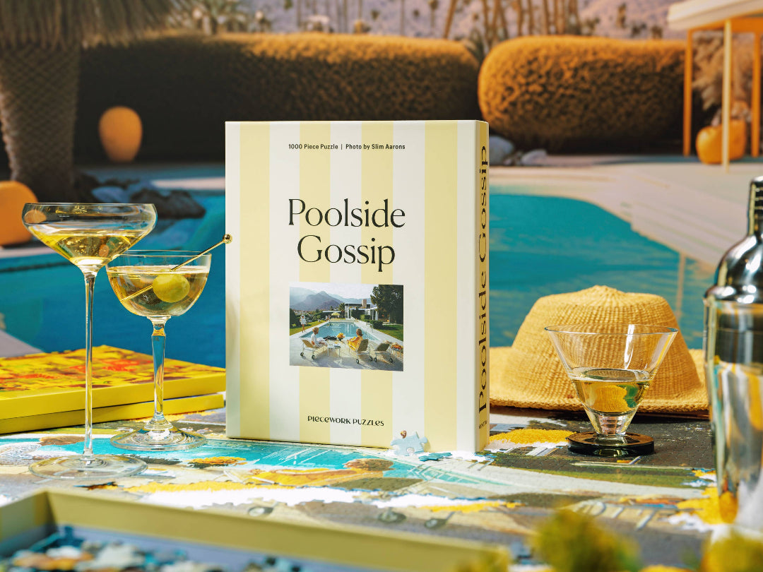 'Poolside Gossip' puzzle box on a poolside table with drinks and decor.