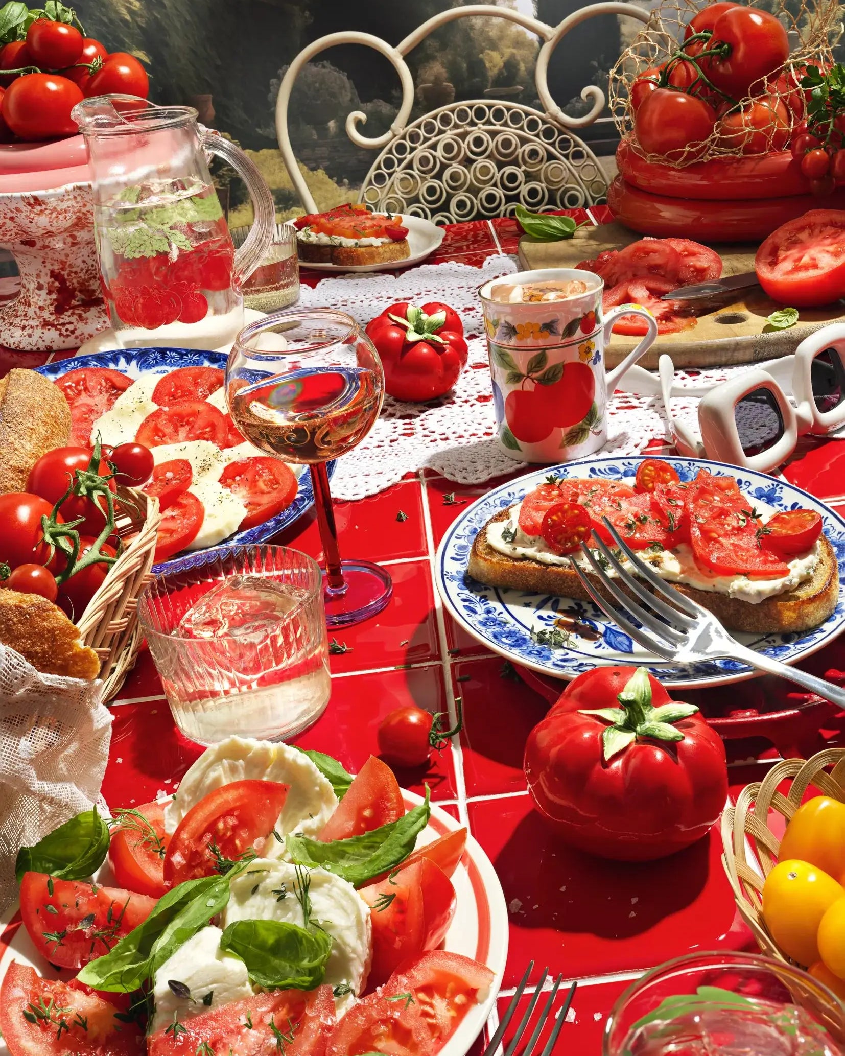 Table setting with tomato-based dishes and drinks on a red tablecloth.