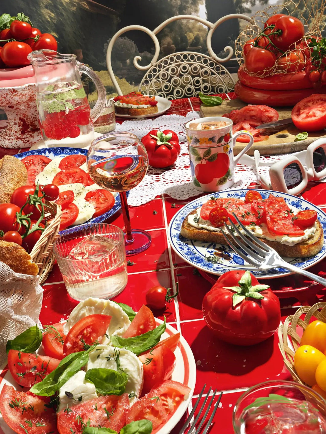 Table setting with tomato-based dishes and drinks on a red tablecloth.