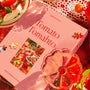 Pink 'Tomato Tomahto' puzzle box with puzzle pieces on a tablecloth with tomatoes.